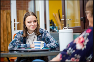 Photo of volunteer mentor with young person having coffee